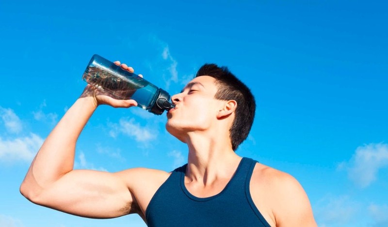 Một cầu thủ đang uống nước trên băng ghế dự bị trong trận đấu bóng đá