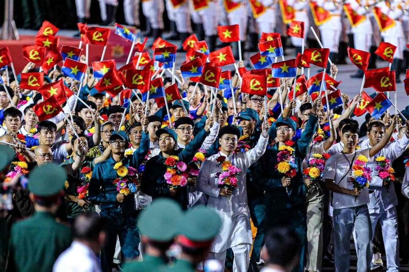 Một đoàn người cùng nhau giơ cao lá cờ Tổ quốc trong một sự kiện cộng đồng