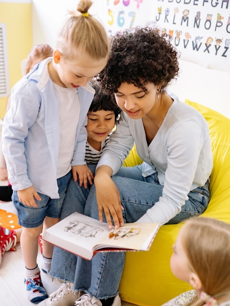 Hình ảnh một cô giáo đang chỉ vào sách cho học sinh